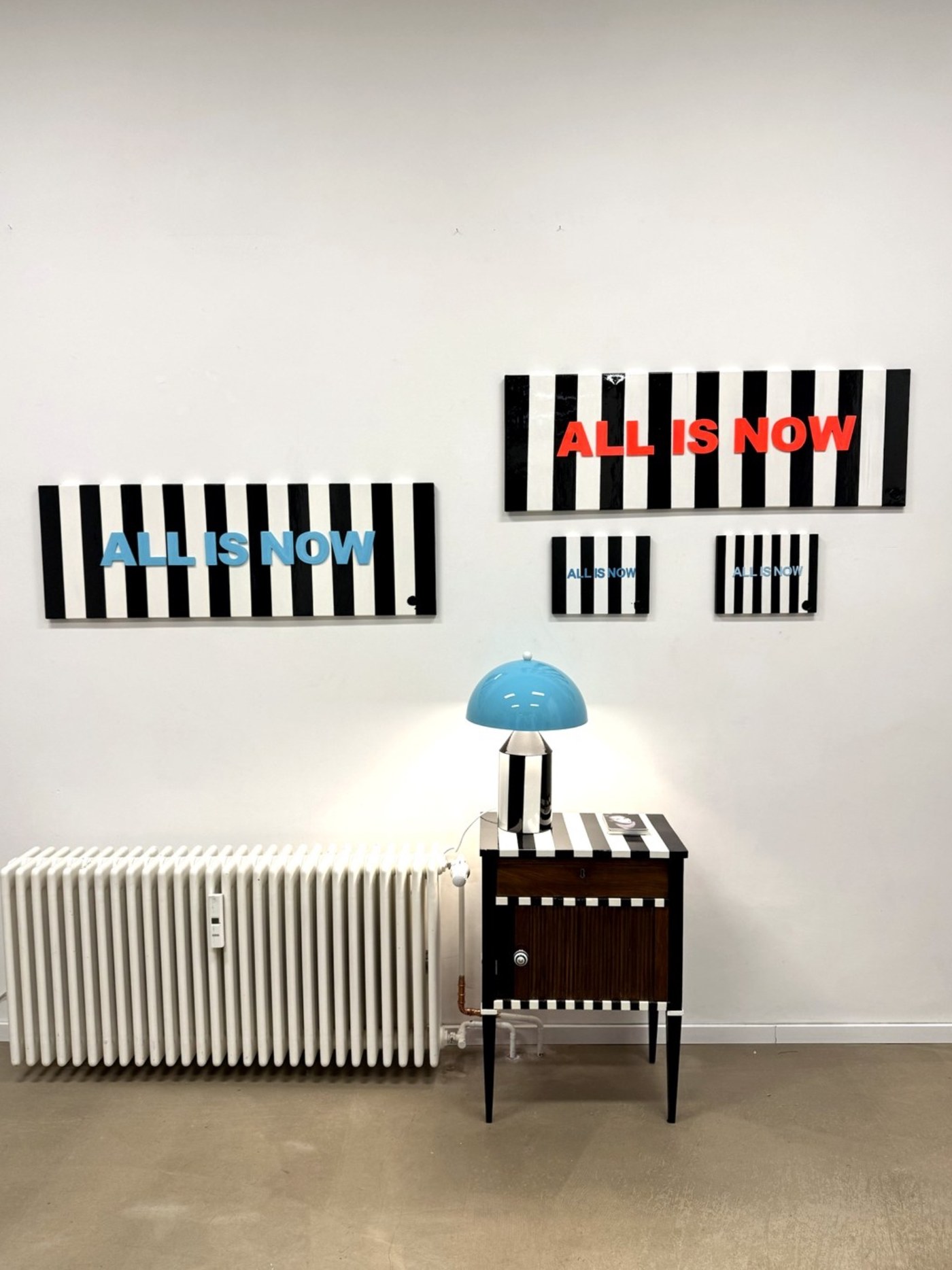 Fiercely Free und Strikingly Bold an der Wand, davor ein gestreiftes Möbelstück mit Lampe im Heartspace Berlin